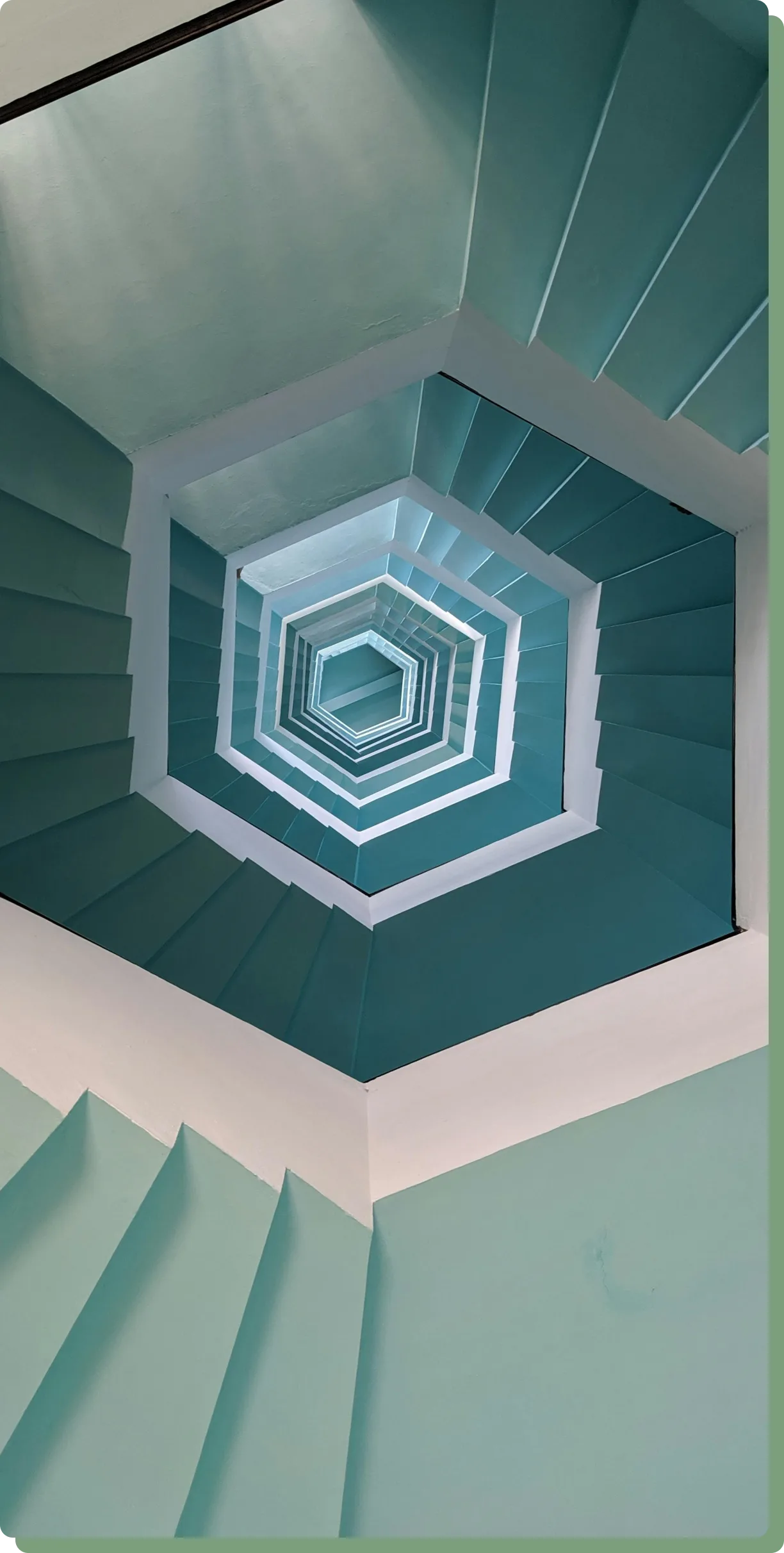 Eine abstrakte eckige Wendetreppe wird von der Vogelperspektive angezeigt. Sie hat weiße und verschiedene Grüntöne.