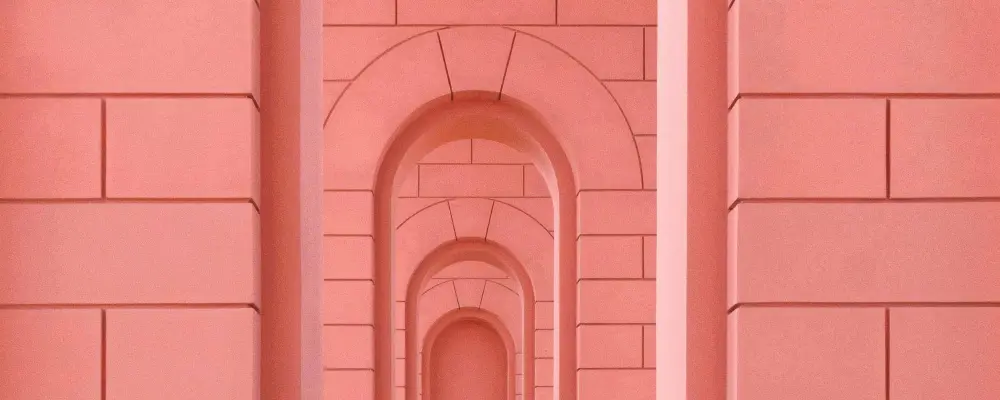 Process Mobile Rosarotes Gebäude mit aneinandergereihten, unterschiedlich großen Torbögen, symbolisiert den strukturierten und zielgerichteten Prozess von RIVNA Partners in der Personalberatung und HR-Lösungen.