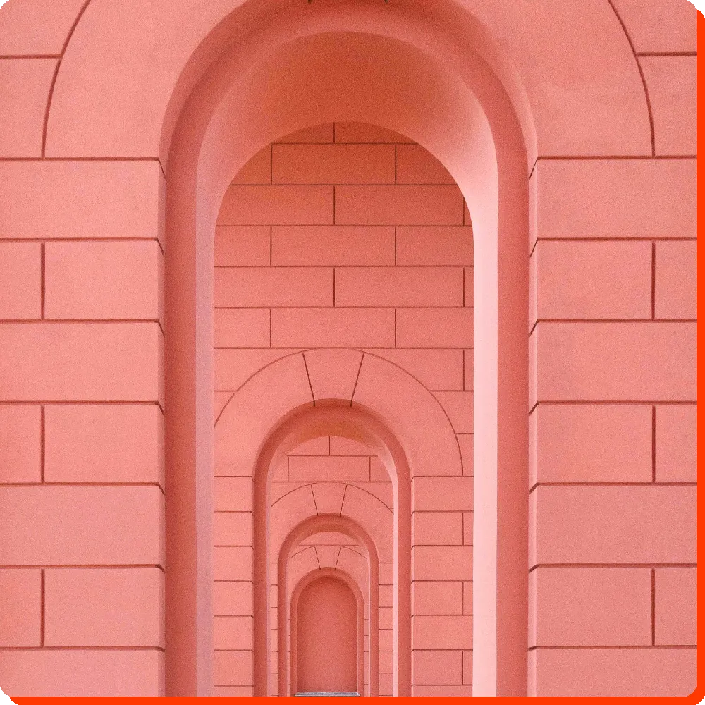 Process Rosarotes Gebäude mit aneinandergereihten, unterschiedlich großen Torbögen, symbolisiert den strukturierten und zielgerichteten Prozess von RIVNA Partners in der Personalberatung und HR-Lösungen.