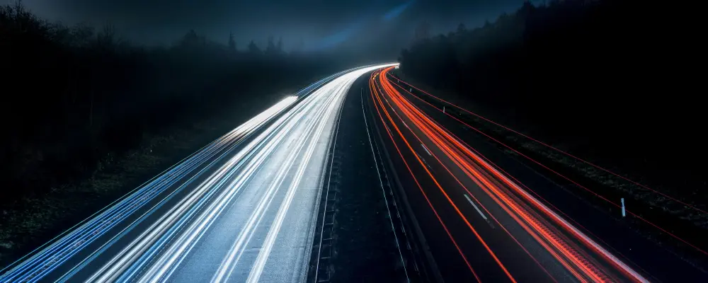 Lichtspuren mehrerer Autos auf einer Autobahn bei Nacht, symbolisch für die Geschwindigkeit und Fokus von Besetzungen von Mitarbeitern.
