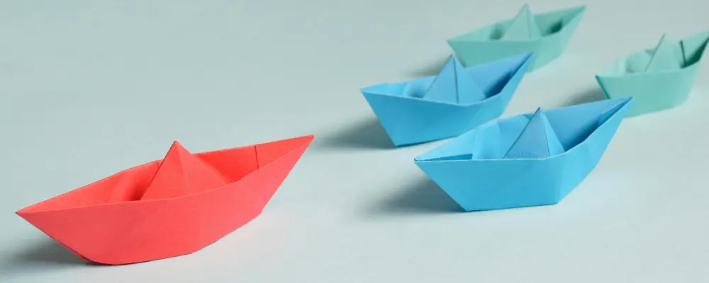 Team Mobile Rotes Papierschiff, gefolgt von blauen Papierschiffen, symbolisiert das Team von RIVNA Partners