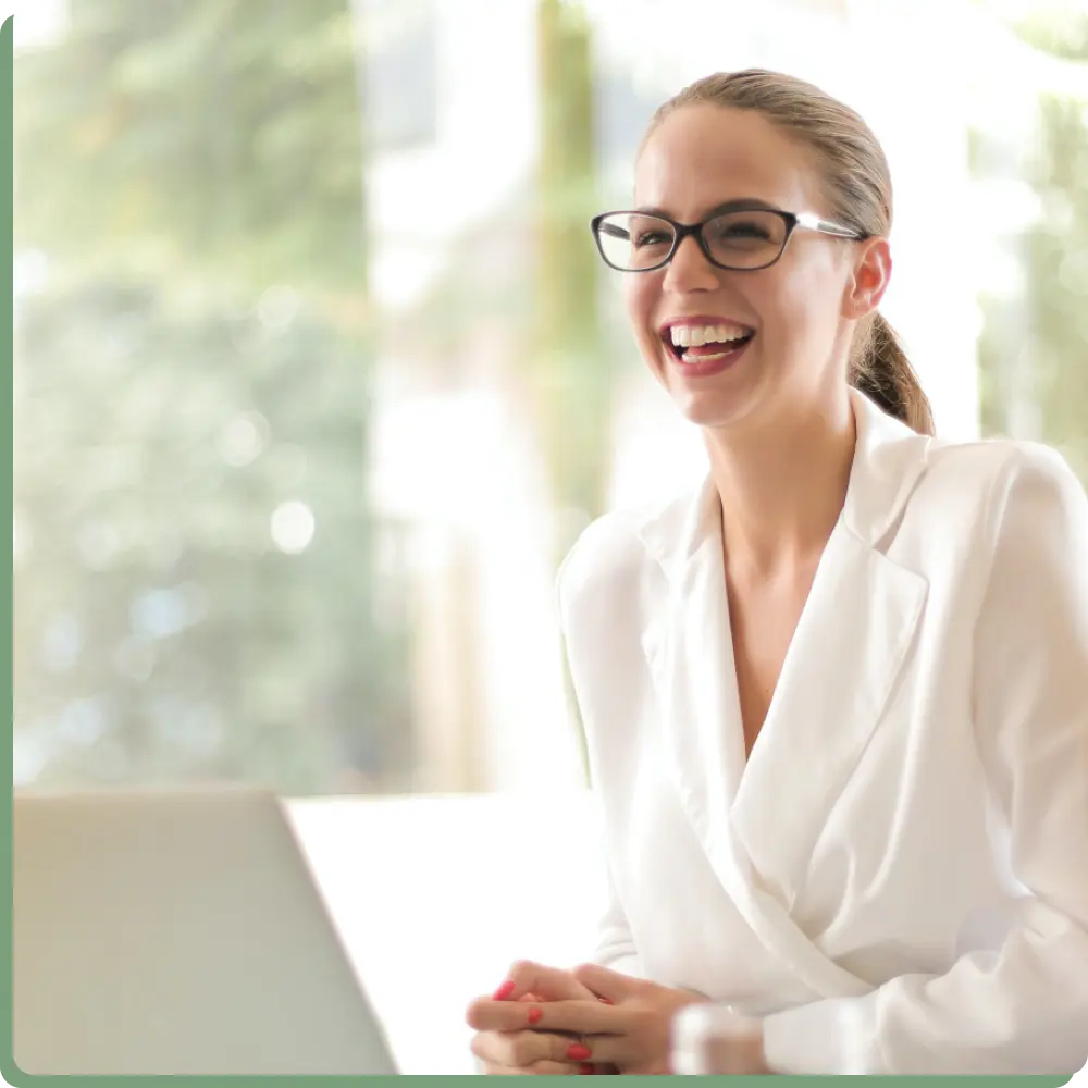 Eine lächelnde junge Frau in Ihrem Büro aus Glas, symbolisch für die Transparenz und klare Einblicke in einer offenen Unternehmenskultur. 